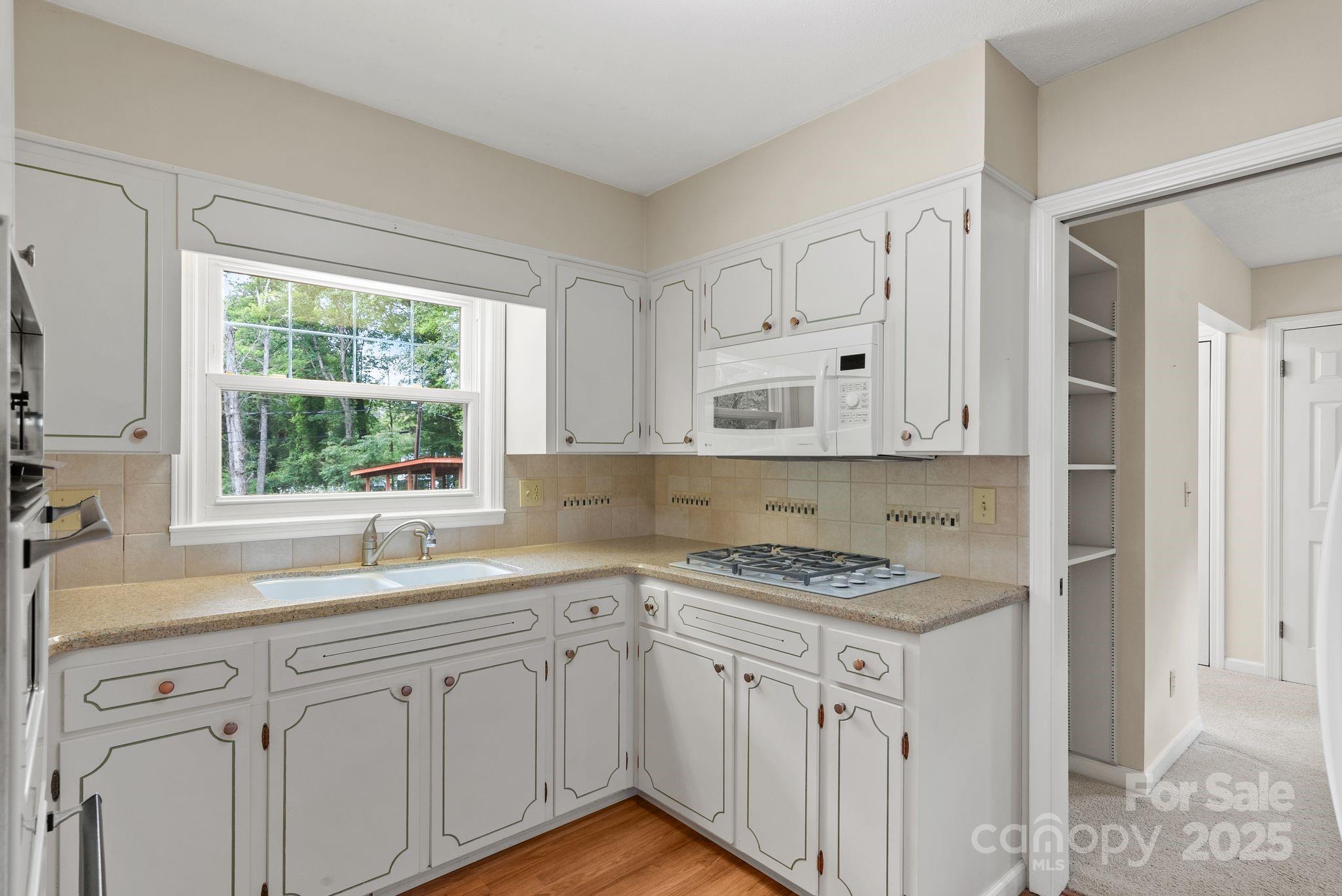 6693 Brevard Road Etowah, NC 28729 - Photo 22 of 42 a kitchen with granite countertop white cabinets sink and window