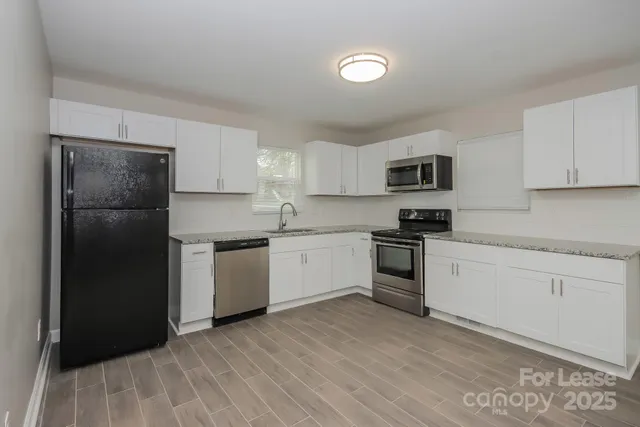 a kitchen with granite countertop white cabinets and stainless steel appliances