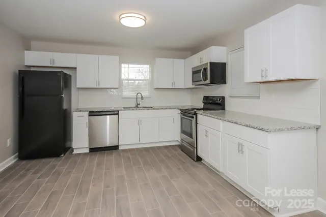 a kitchen with stainless steel appliances granite countertop a refrigerator sink and white cabinets