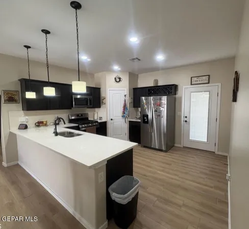 a large white kitchen with a refrigerator a stove a sink and a wooden floor