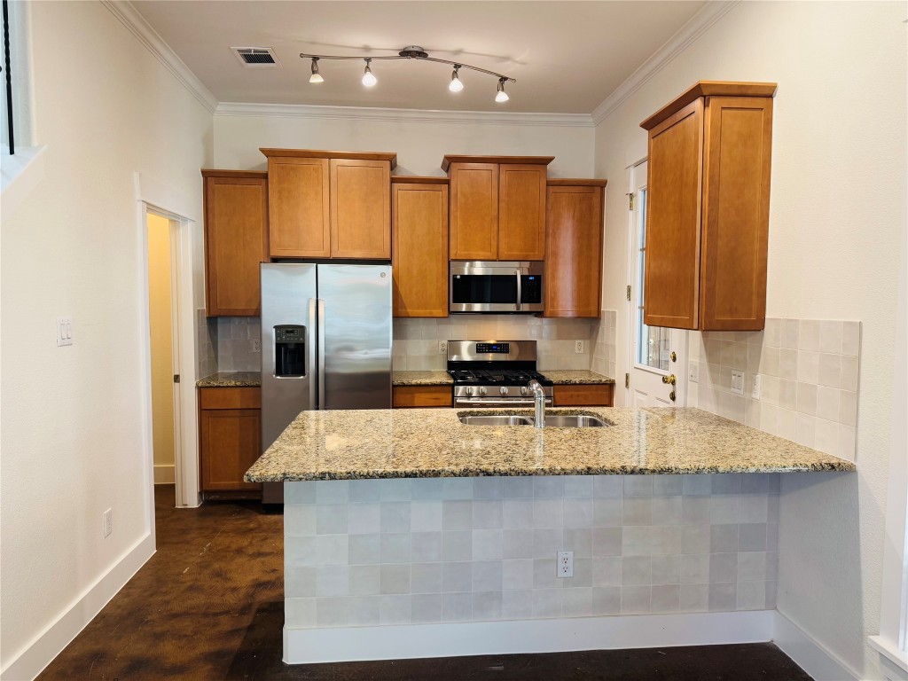 609 Franklin Boulevard, Unit A Austin, TX 78751 - Photo 1 of 19 Kitchen with maple cabinets, decorative backsplash, appliances with stainless steel finishes, granite countertops, and track lighting