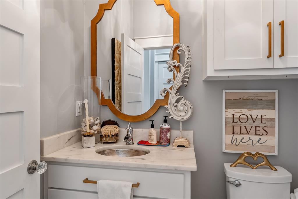 16241 Big Oak Bay Road Tyler, TX 75707 - Photo 14 of 40 Bathroom vanity featuring a hammered metal sink, stone countertop, white shaker-style cabinetry, and a decorative gold-framed mirror