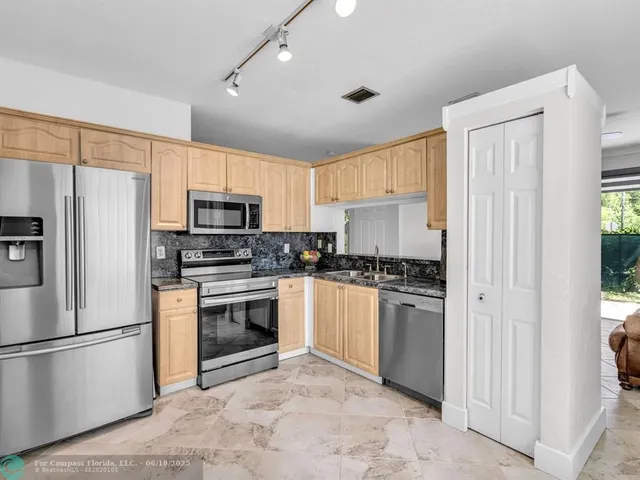 a kitchen with stainless steel appliances granite countertop a refrigerator stove a sink dishwasher and microwave