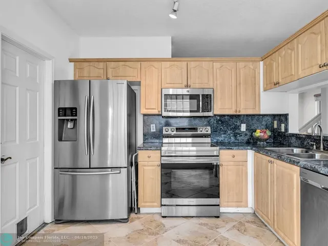 a kitchen with stainless steel appliances a refrigerator sink and microwave