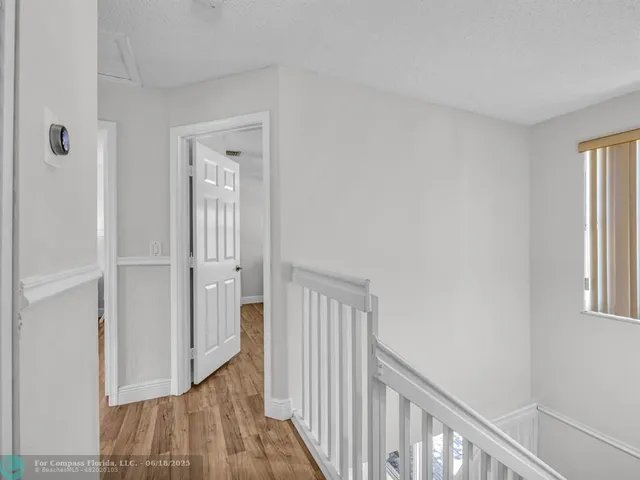 a view of a hallway with wooden floor and windows
