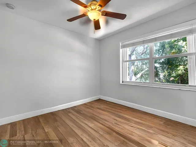 a view of an empty room with window and wooden floor