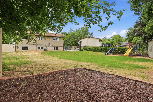629 King Circle Layton, UT 84041 - Photo 25 of 26 Expansive backyard featuring a combination of natural lawn and mulched areas, bordered by mature trees and a privacy fence