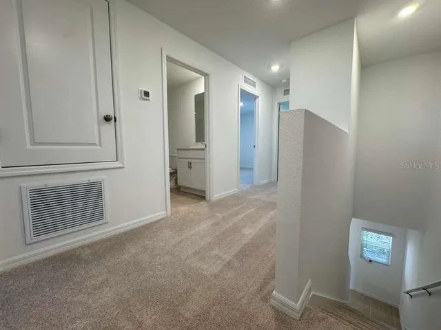 a view of an empty room with wooden floor and a bathroom