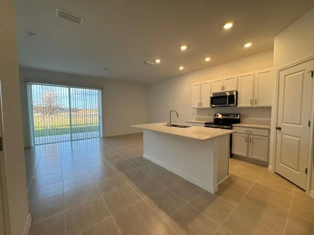 a large kitchen with stainless steel appliances a large counter top a stove a microwave and a refrigerator