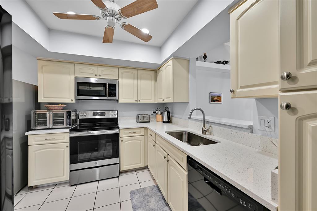 10788 Waterberry Drive Boca Raton, FL 33498 - Photo 9 of 30 a kitchen with stainless steel appliances granite countertop a sink a stove top oven a refrigerator with island and cabinets