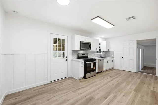 a kitchen with stainless steel appliances a white refrigerator a sink a stove and cabinets