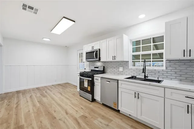 a kitchen with granite countertop a sink stainless steel appliances and cabinets