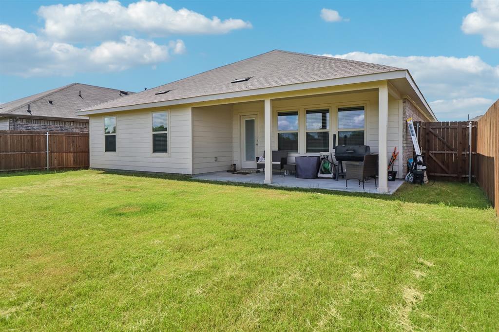 1453 Millstead Rill Road Caddo Mills, TX 75135 - Photo 38 of 40 Expansive backyard featuring a covered patio, multiple windows, a rear entry door, and wood fencing