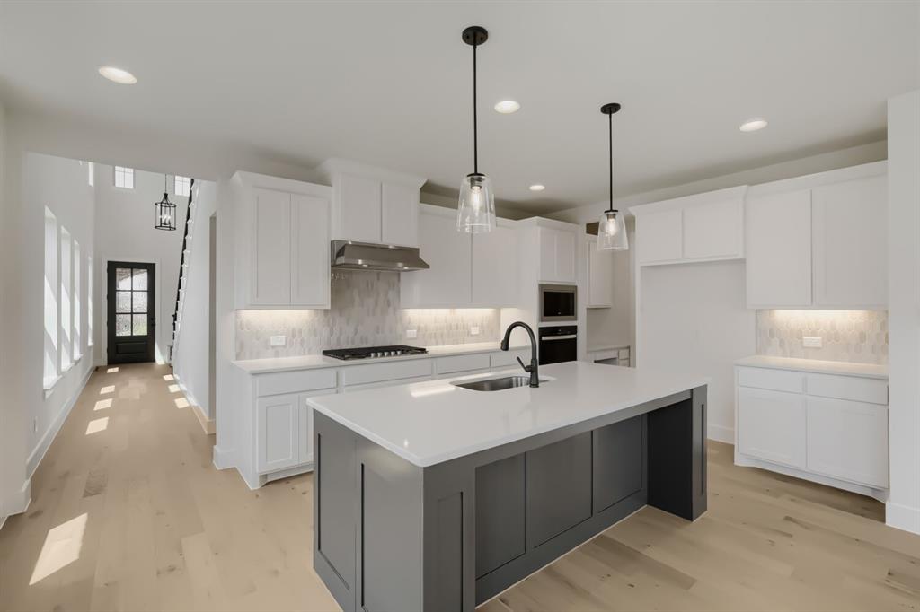 824 Stone Grv Road Lavon, TX 75166 - Photo 9 of 26 Modern kitchen featuring a large central island with a sink, white cabinetry, a built-in oven, and a gas range