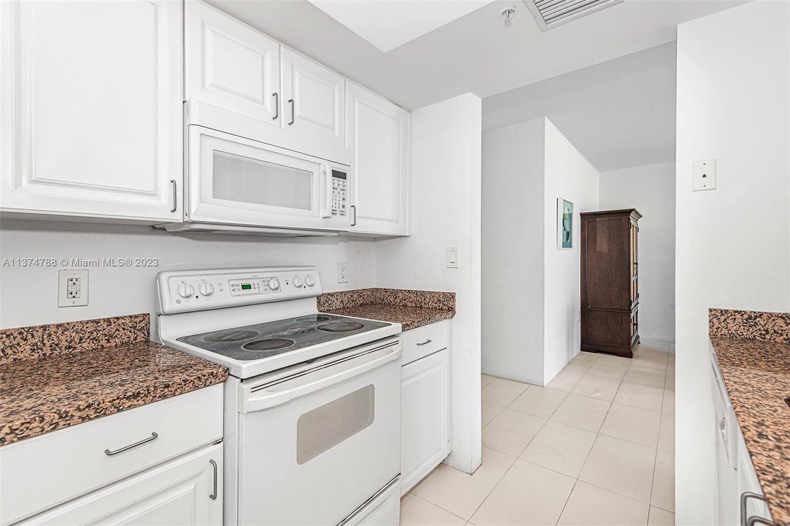 90 Alton Road, Unit 905 Miami Beach, FL 33139 - Photo 9 of 33 a kitchen with granite countertop white cabinets and appliances