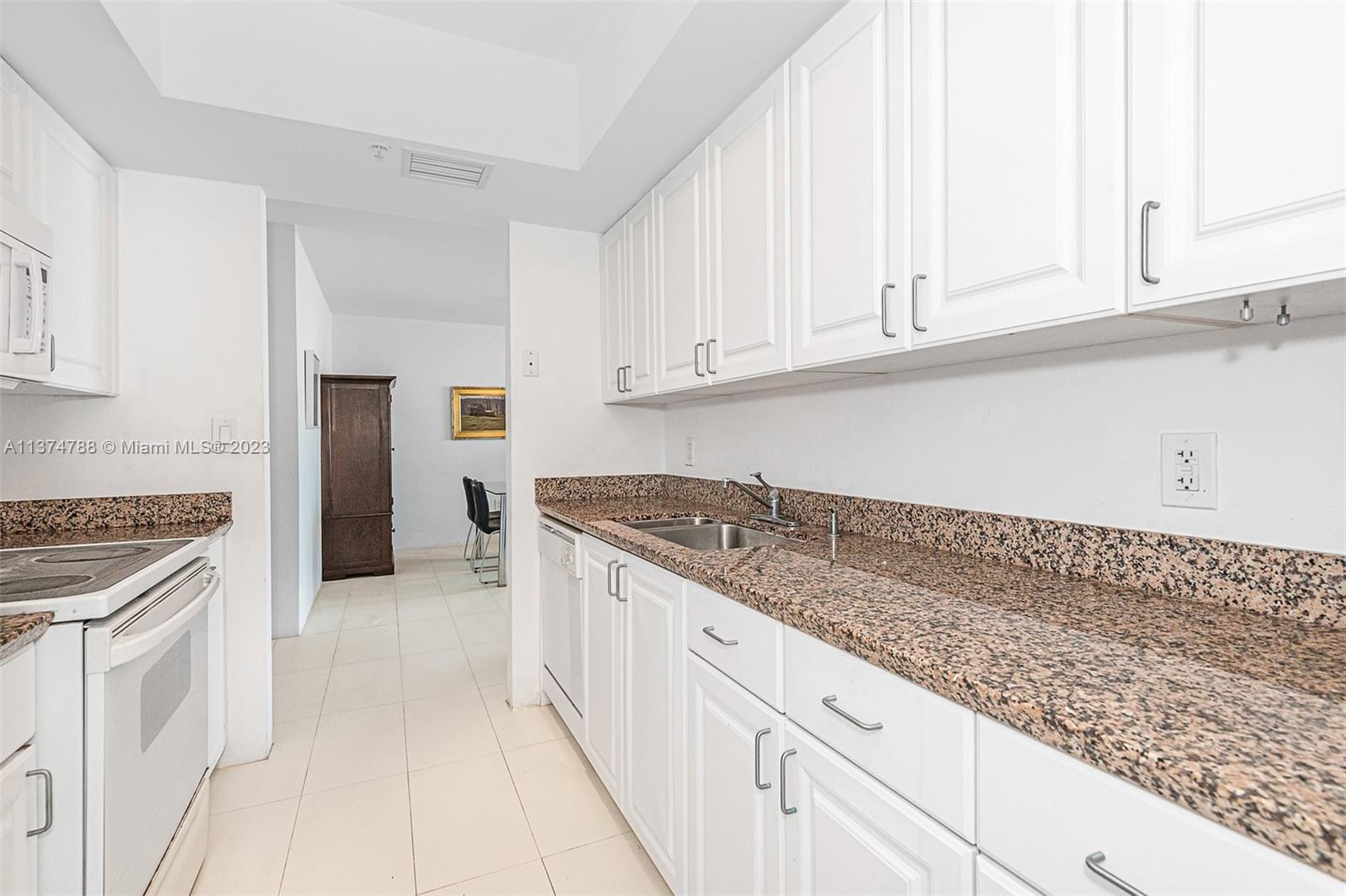 90 Alton Road, Unit 905 Miami Beach, FL 33139 - Photo 10 of 33 a kitchen with granite countertop white cabinets and white appliances