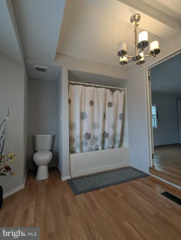 a view of a hallway with wooden floor and a livingroom