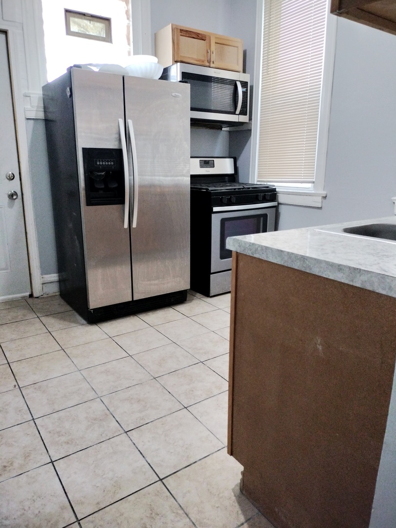 6719 South Sangamon Street, Unit 1 Chicago, IL 60621 - Photo 14 of 23 a metallic refrigerator freezer sitting in a kitchen