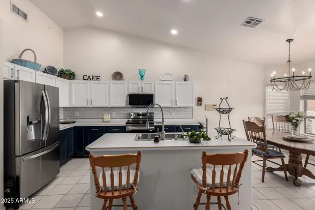 a kitchen with stainless steel appliances granite countertop a sink a stove a refrigerator cabinets and chairs