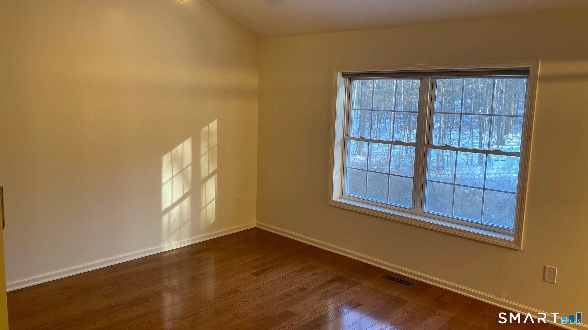 403 Larson Drive, Unit 403 Danbury, CT 06810 - Photo 13 of 34 an empty room with wooden floor and windows