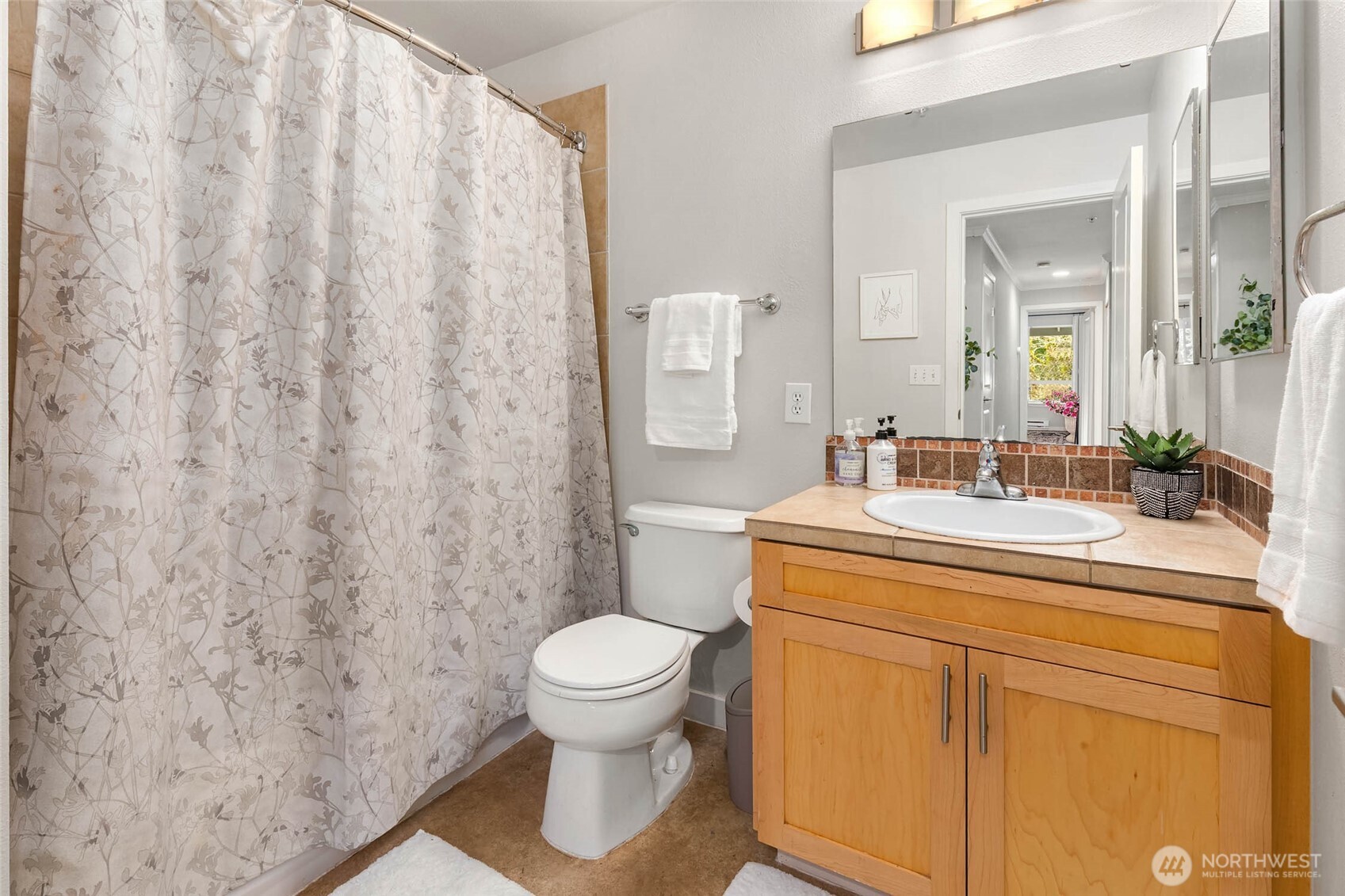12023 Northeast 204th Place, Unit E302 Bothell, WA 98011 - Photo 21 of 26 a bathroom with a sink a toilet and a mirror