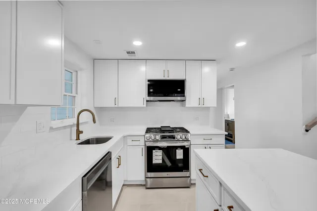 a kitchen with granite countertop a sink stove and white cabinets