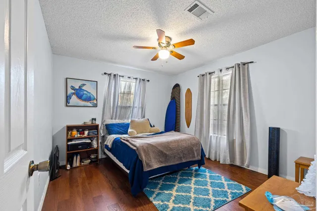 a bedroom with a bed a couch and a flat tv screen on dresser