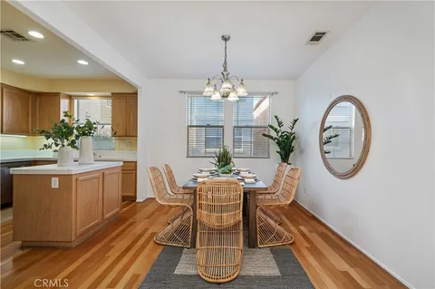 a dining room with chandelier fan and wooden floor