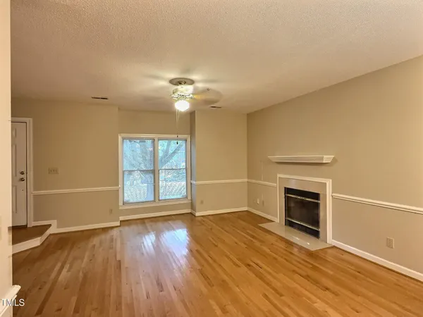 an empty room with wooden floor fireplace and windows