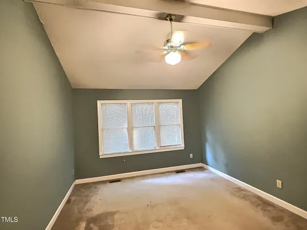 an empty room with a chandelier fan and windows
