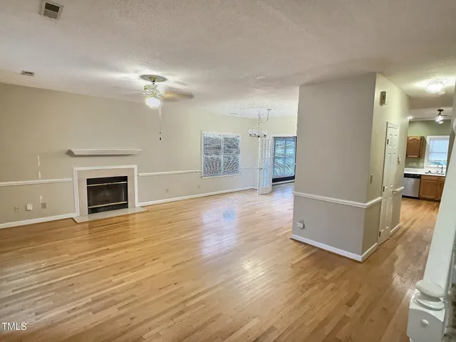 a view of a livingroom with wooden floor and a kitchen space