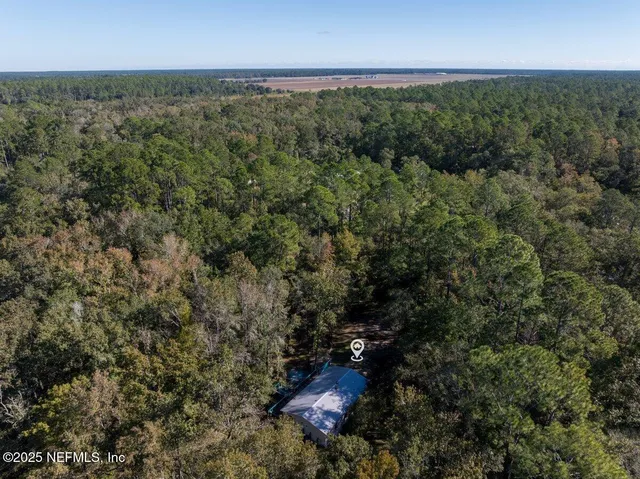 an aerial view of residential house with outdoor space and trees all around