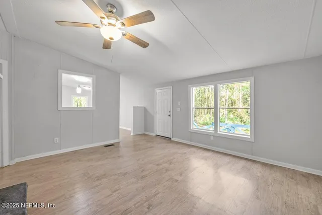 an empty room with windows and ceiling fan