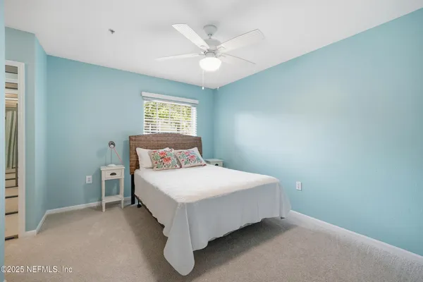 a bedroom with a large bed and a chandelier fan