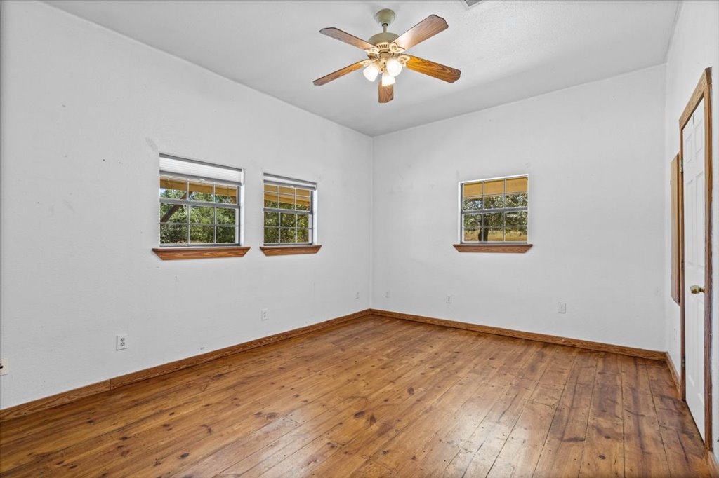 555 Harmon Hills Road, Unit A Dripping Springs, TX 78620 - Photo 18 of 29 Hardwood floors and a ceiling fan create a comfortable and inviting atmosphere.