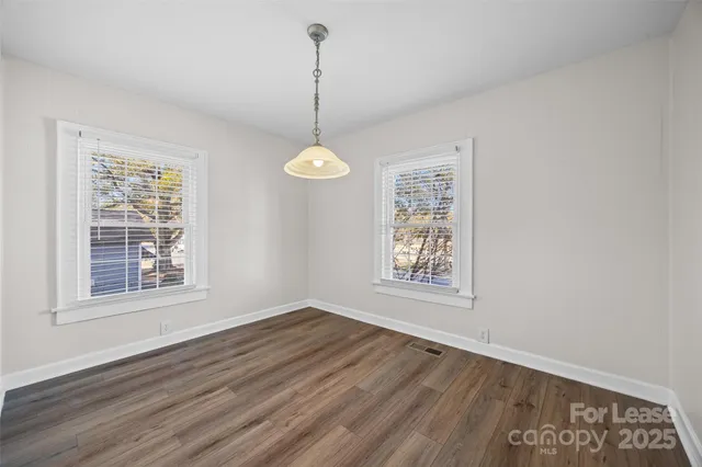a view of an empty room with window and wooden floor