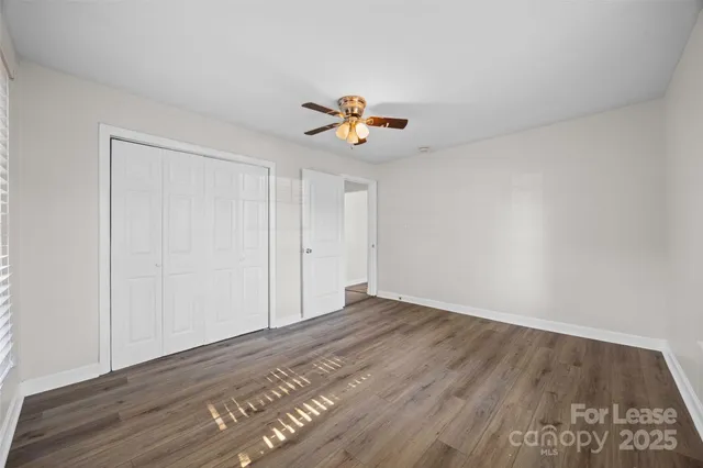 a view of a room with wooden floor and a ceiling fan