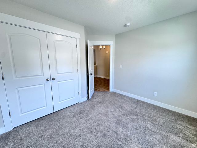 12339 Remy Road, Unit 422 Herriman, UT 84096 - Photo 3 of 36 Unfurnished bedroom featuring carpet floors, a closet, and a textured ceiling