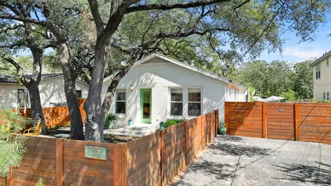 a view of a house with wooden fence next to a yard
