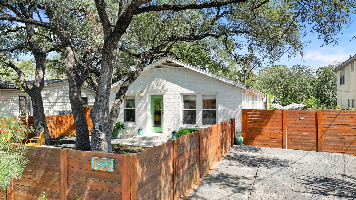 a view of a house with wooden fence next to a yard
