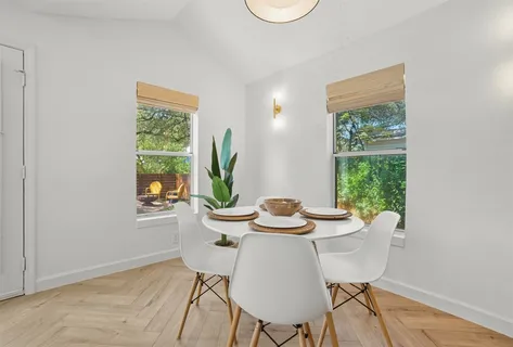 a view of a dining room with furniture a potted plant and a window