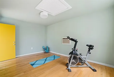 a room with gym equipment and wooden floor