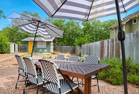 a view of a patio with table and chairs under an umbrella with a small yard