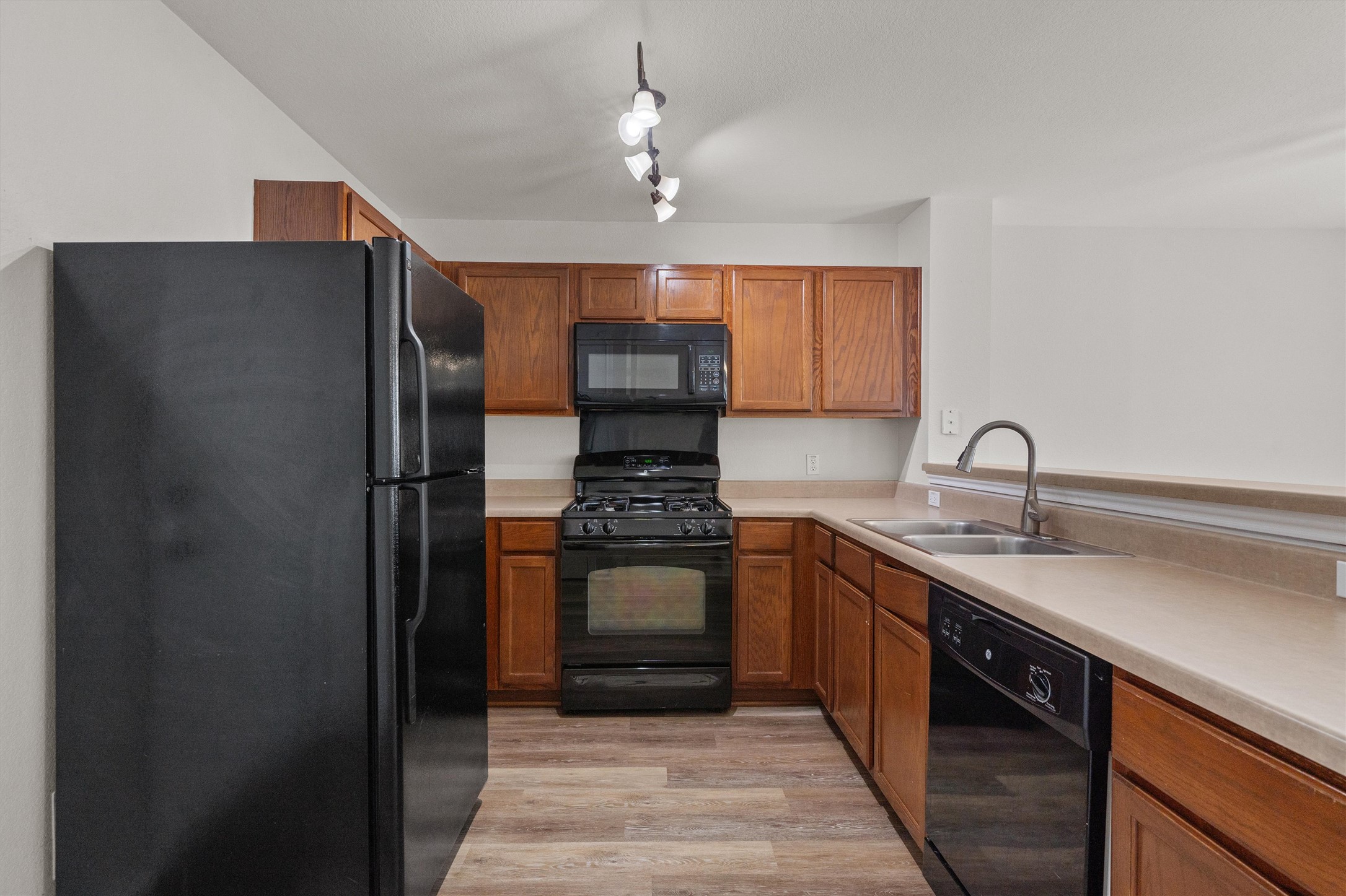 5825 Silver Screen Drive Austin, TX 78747 - Photo 11 of 40 Step into a well-appointed kitchen featuring sleek black appliances and warm wood cabinetry.