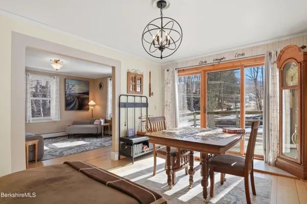 a dining room with wooden floor a chandelier a wooden table and chairs