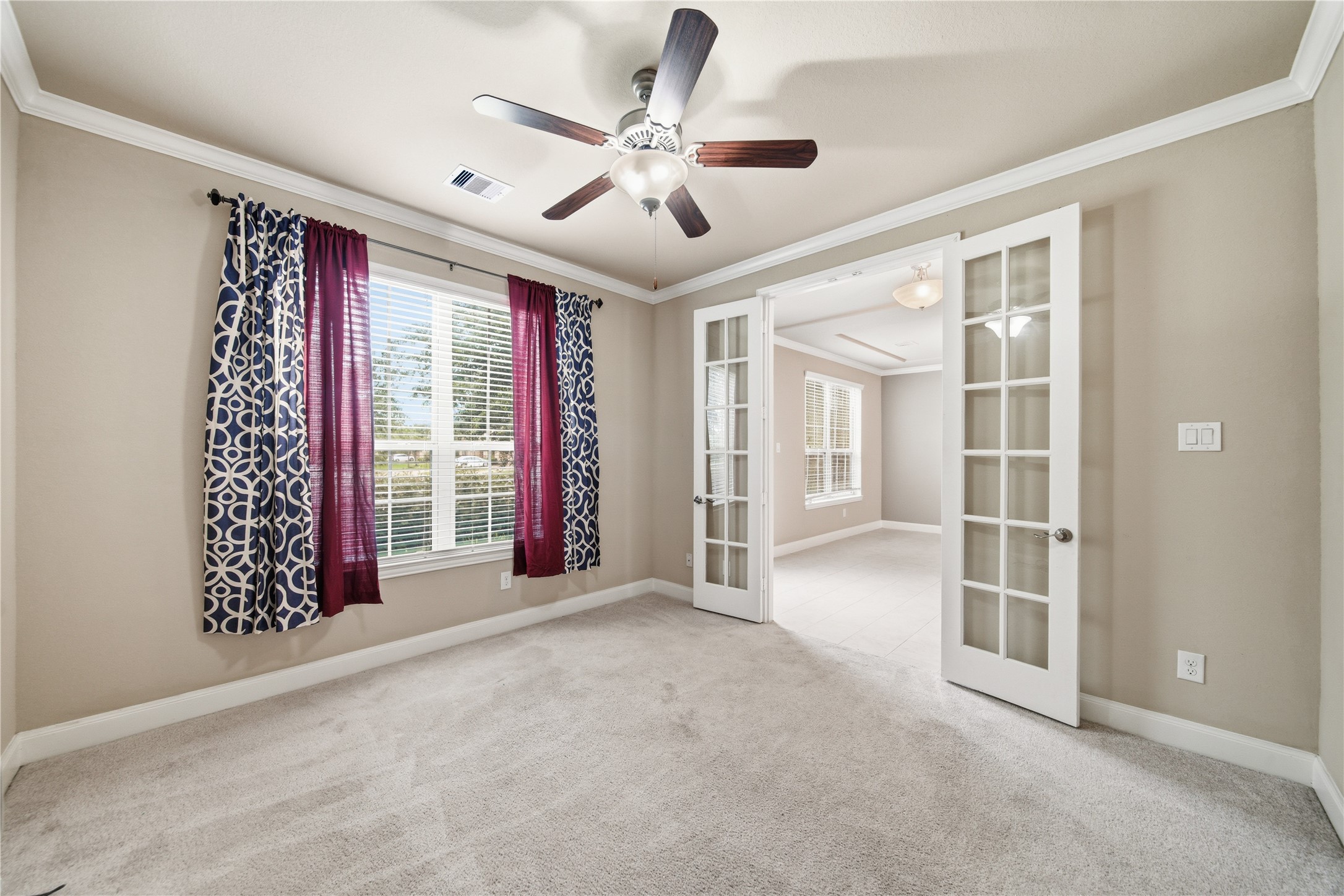 5303 Mesquite Willow Lane Rosharon, TX 77583 - Photo 7 of 32 This room features soft carpet flooring, neutral walls, and a ceiling fan. It has large windows, allowing natural light to fill the space. French doors open to an adjacent room, enhancing the open feel. Perfect for a home office or study.