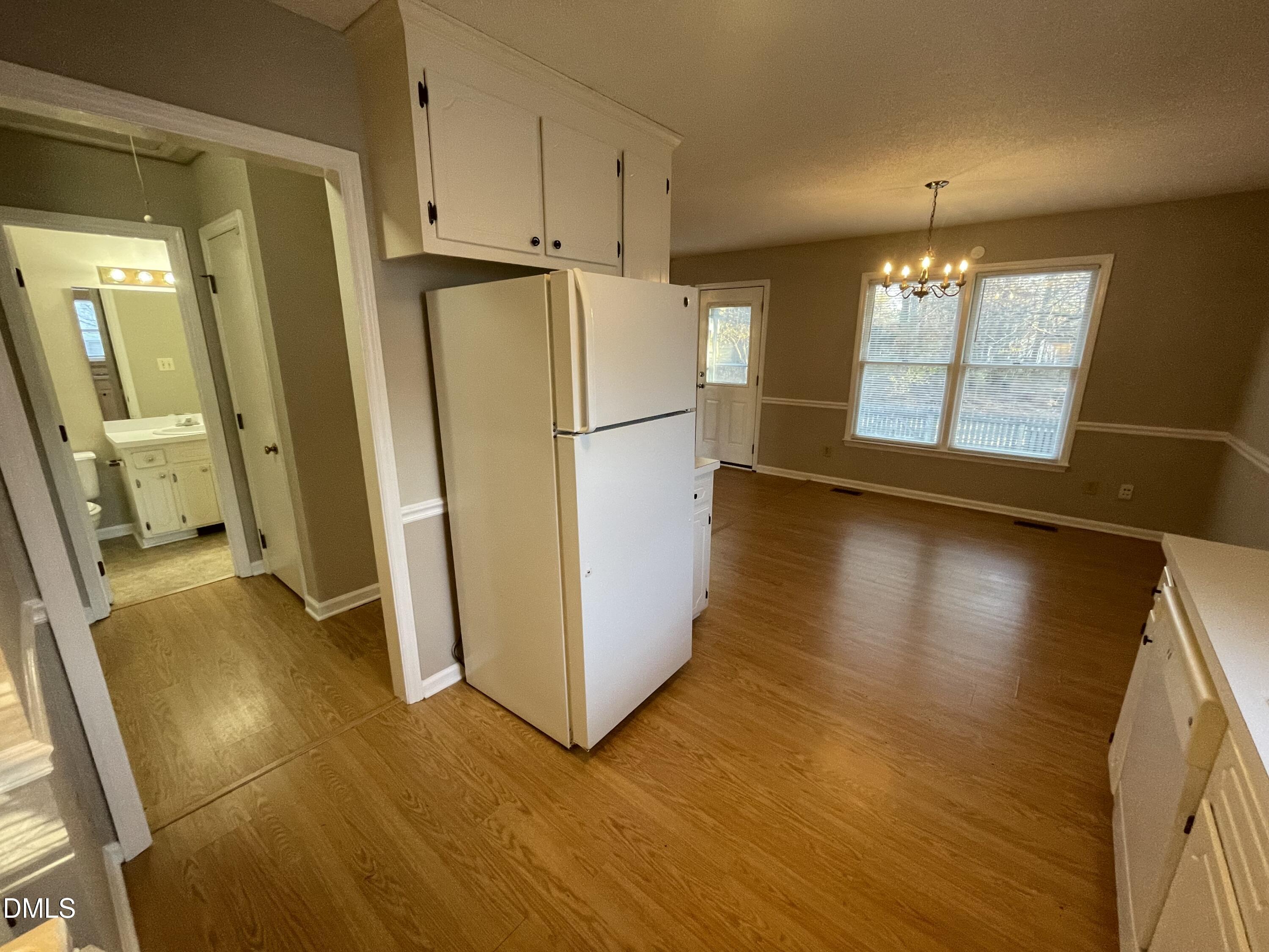 4116 Lodge Allen Court Raleigh, NC 27616 - Photo 11 of 20 a view of a refrigerator in kitchen and an empty room with wooden floor