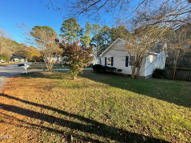 a yellow house sitting in middle of the middle of a yard
