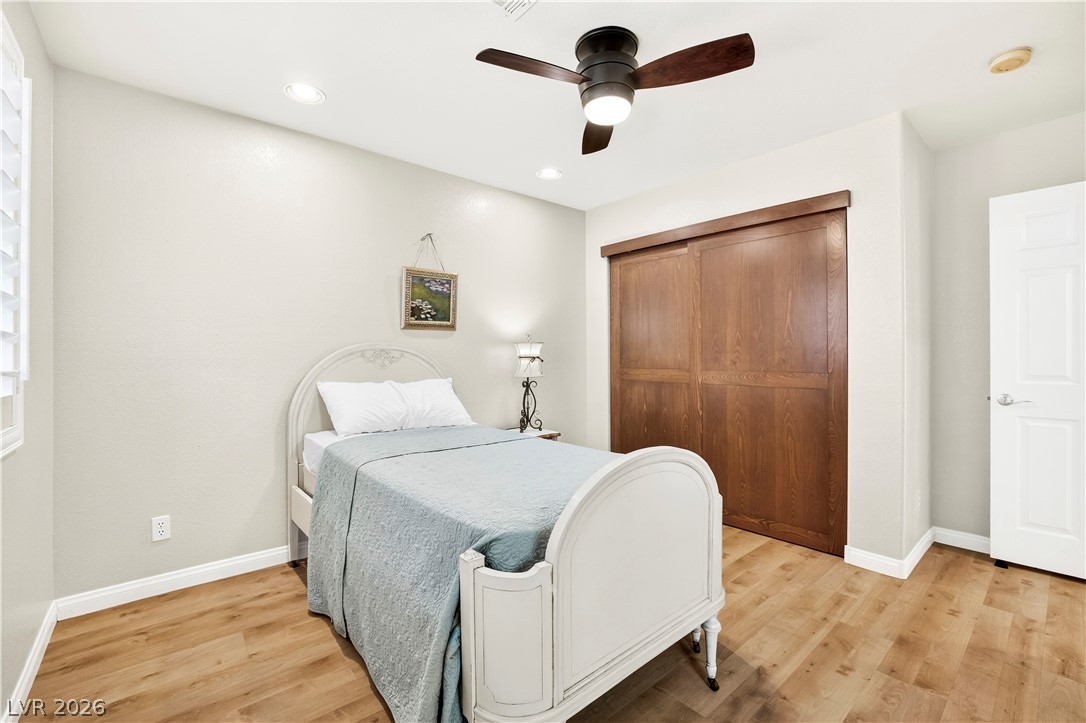 1135 Calico Ridge Drive Henderson, NV 89011 - Photo 43 of 86 A well-lit bedroom features warm wood-look flooring and convenient closet storage with sliding doors.