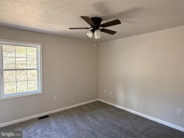an empty room with a window and a fan